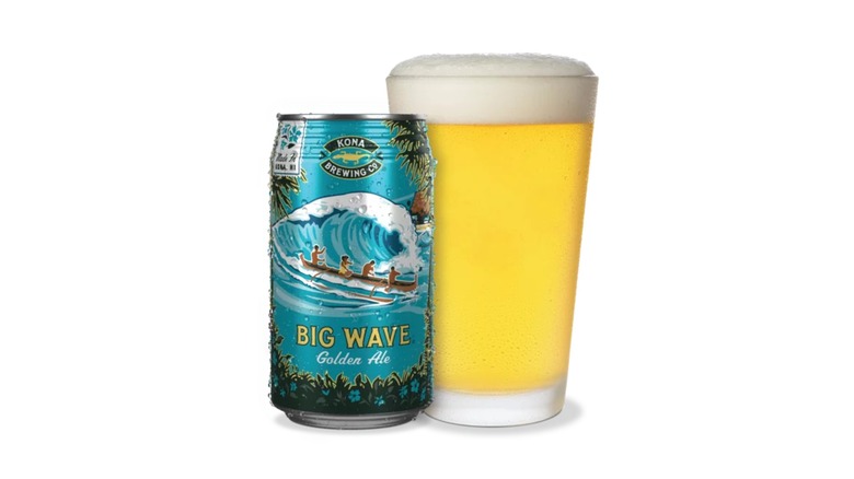 Teal can of Kona Big Wave Golden Ale next to a full pint glass of beer on a white background