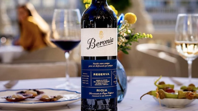 Bottle of Beronia Rioja Reserva on outdoor table with white tablecloth, tapas dishes, and glasses of wine