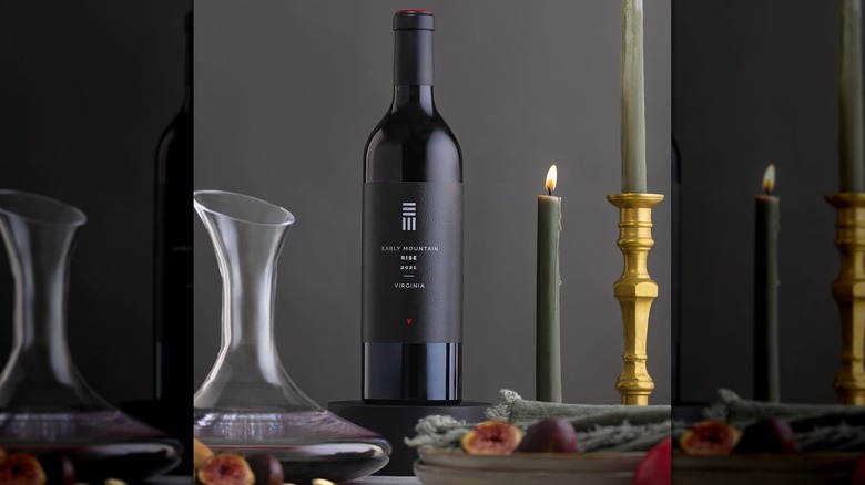 Bottle and decanter of Early Mountain Vineyards RISE wine with candles on table.