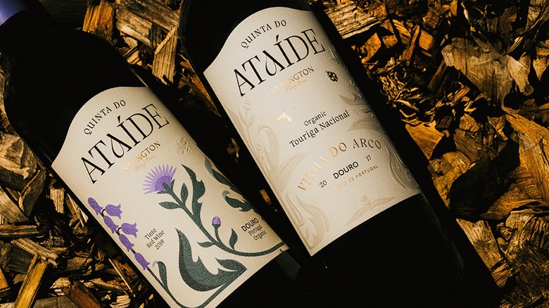 Bottles of Quinta do Ataíde red wine arranged on woodchips outdoors for photo.