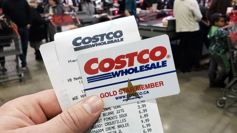 holding costco card and grocery receipt