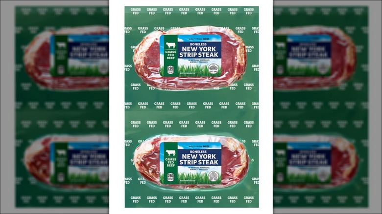 Two boneless New York strip steaks in plastic packaging against white background.