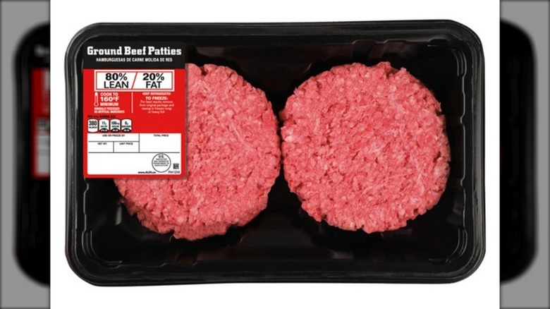 Package of ground beef patties against white background.
