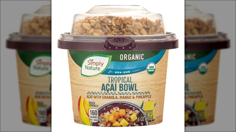 Small plastic acai bowl with granola and fruit against white background.
