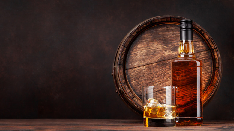 Bottle of whiskey, glass and barrel