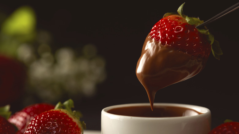 dipping strawberry in bowl of chocolate