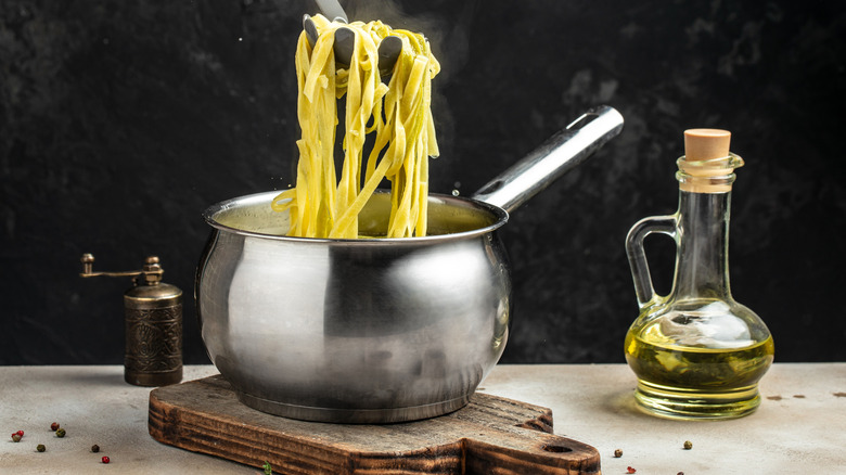 A pot of boiling pasta with a jar of oil