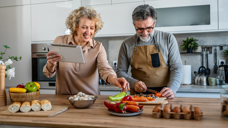A couple cooking together following a recipe on a tablet