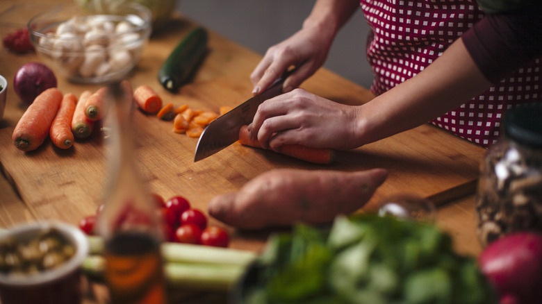 A woman chopping a variety of vegetables