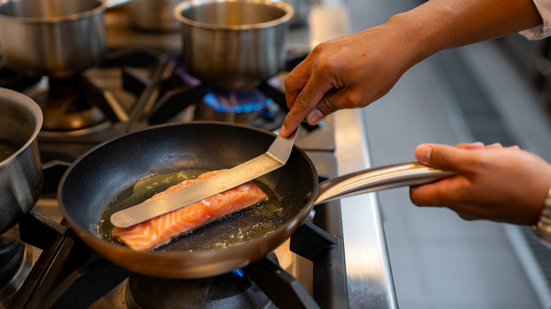 A chef searing a fish fillet