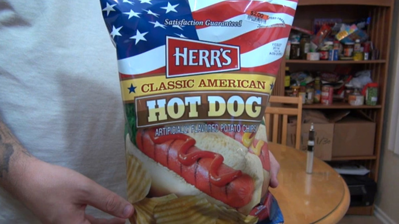 man holding bag of Herr's Classic American Hot Dog chips