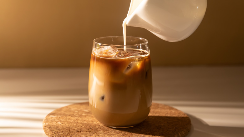 cream poured into a cup of coffee 