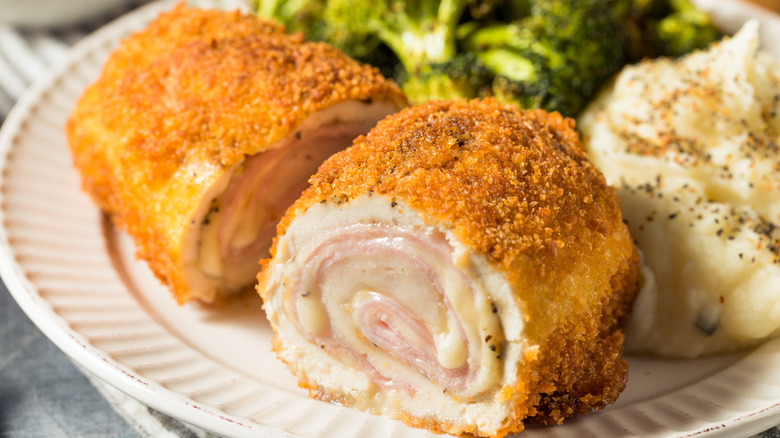 Plated chicken cordon bleu with servings of cooked broccoli and mashed potatoes.