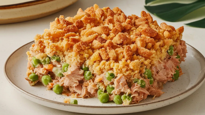 Plated tuna casserole studded with green peas and a crispy topping.