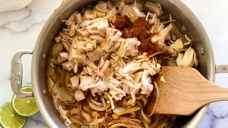 Shredded jackfruit in pot with garlic, onions, and spices
