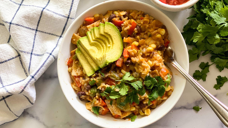 Close up of a bowl of stovetop enchiladas being stirred by a wooden spoon