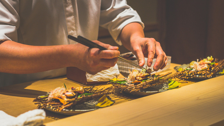 Chef delicately preparing plates with chopsticks at omakase restaurant