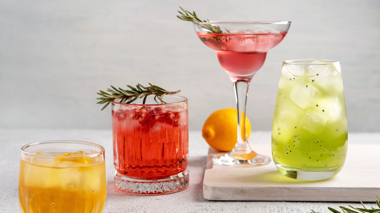 Four colorful cocktails lined up against a blank background
