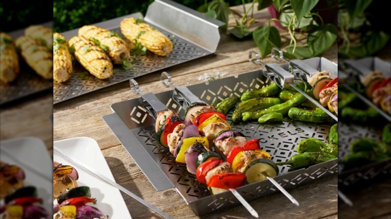 Two metal barbecue trays with skewers.
