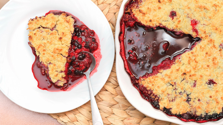 Slice of gooey blackberry cobbler cut from the whole cobbler and served on a plate with spoon