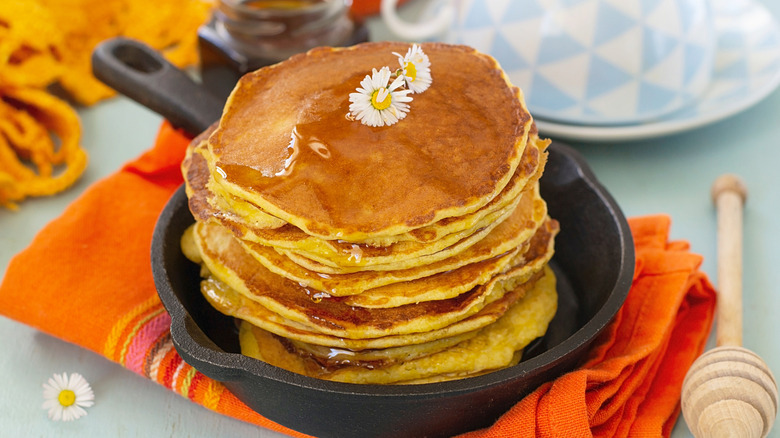 Stack of thin pancakes, or hoe cakes, in cast iron pan topped with daisy flower