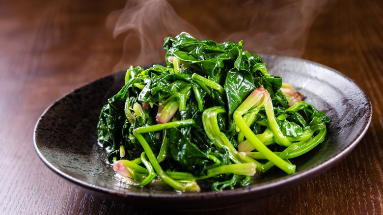 Sauteed kilt greens made with spinach steaming on plate on wooden table