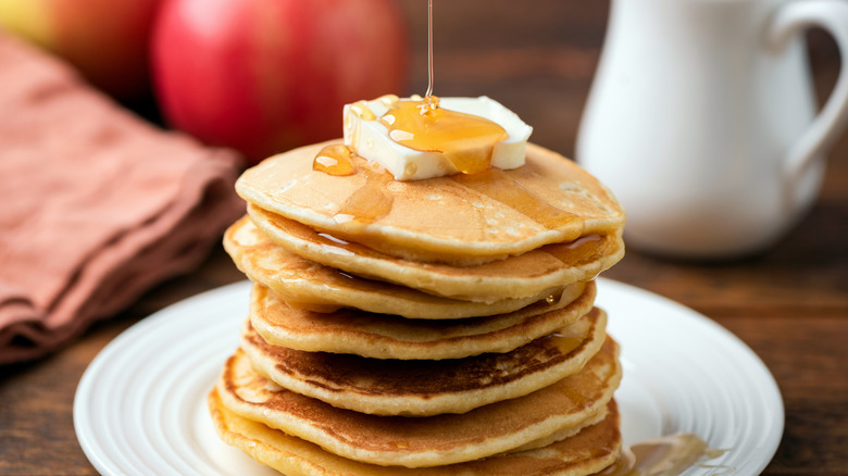 A tall stack of pancakes with butter and syrup