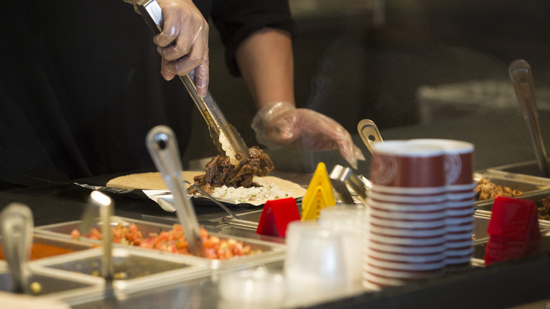 Chipotle employee prepares burrito