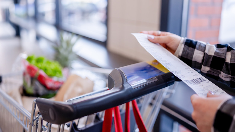 Shopper checking their receipt as they leave grocery store.