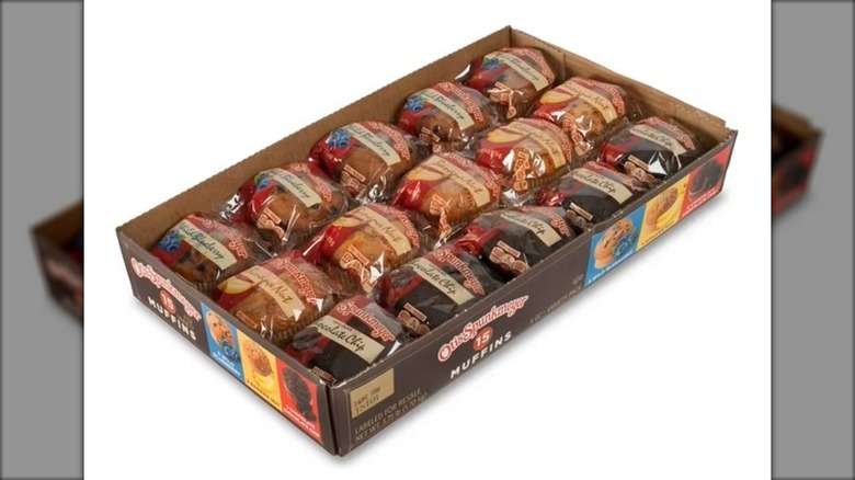 Box of assorted, individually wrapped muffins against white background.