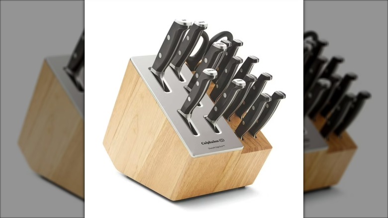 Wood and steel knife block containing knives and pair of shears against white background.