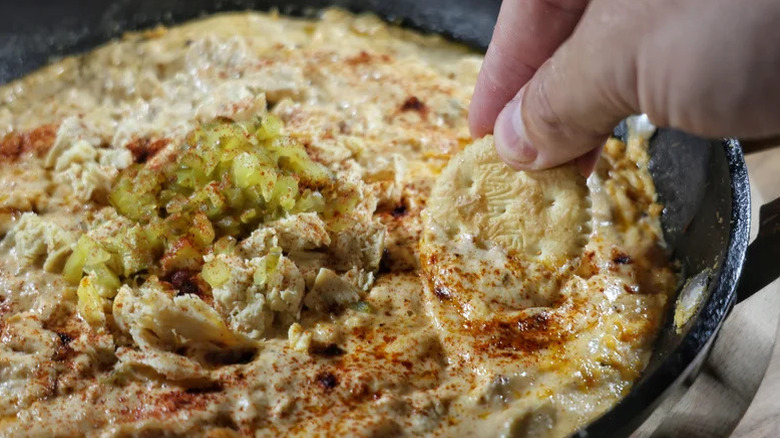 Hand scooping Nashville hot chicken dip