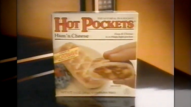Screenshot from Hot Pockets '80s commercial featuring box of hot pockets ham and cheese snacks in front of microwave