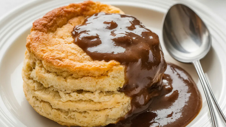 Biscuit with chocolate gravy on a white plate with a spoon