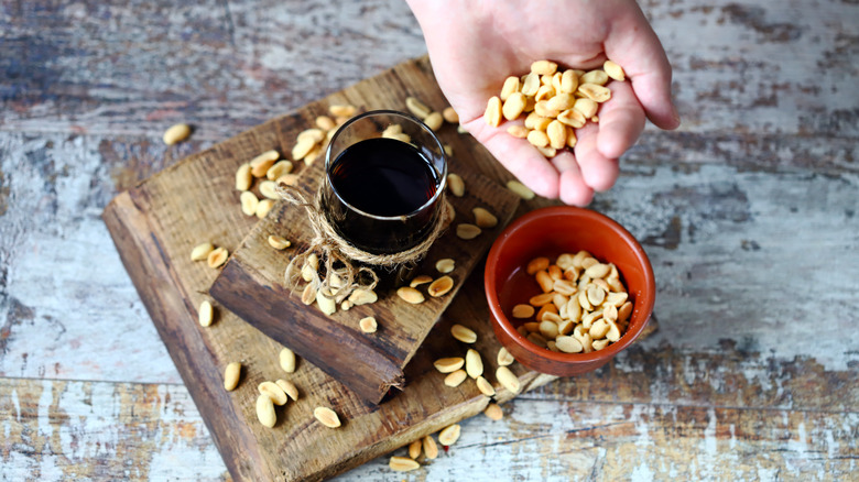 A person's hand putting peanuts into a glass of Coke