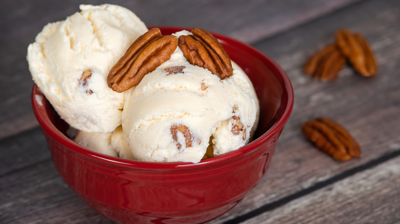 Butter pecan ice cream in a red bowl with pecans