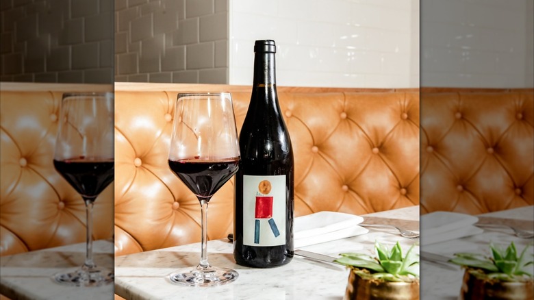 Glass of Nicolas Reau Cabernet Franc with bottle next to it with tan leather upholstery in the background
