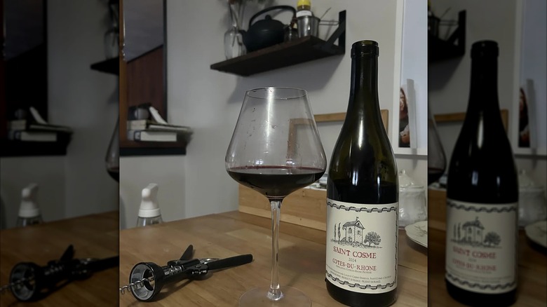 Bottle of Saint Cosme Cotes du Rhone with glass and corkscrew on table