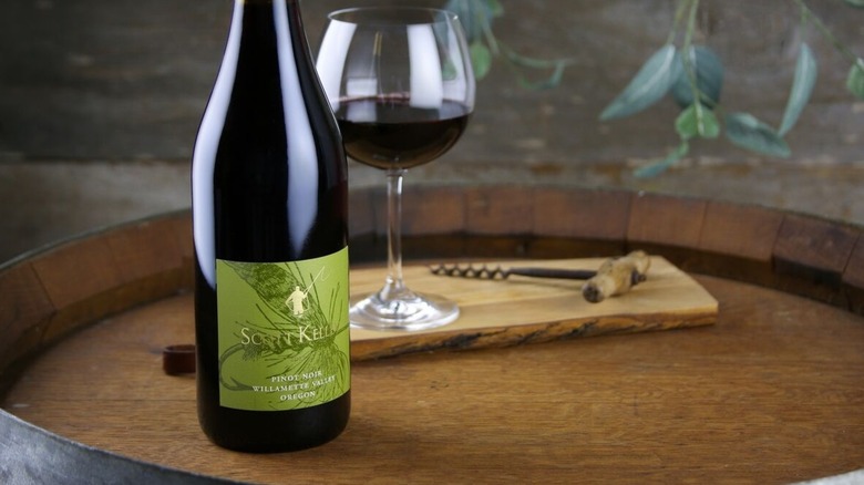 Bottle of Scott Kelley Willamette Valley Pinot Noir on barrel next to glass of red wine