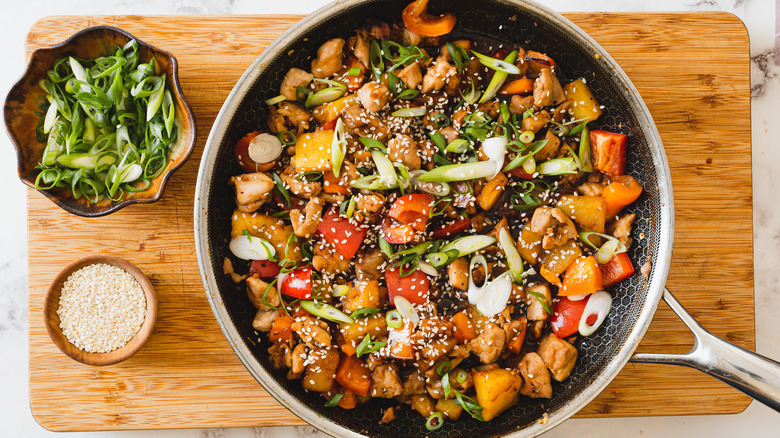 grilled pineapple teriyaki chicken in pan with scallions and sesame seeds