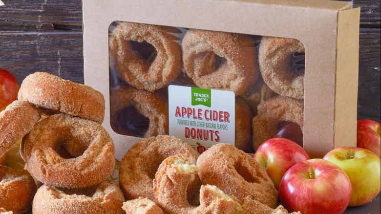 Package of Trader Joe's Apple Cider Donuts surrounded by donuts and apples.