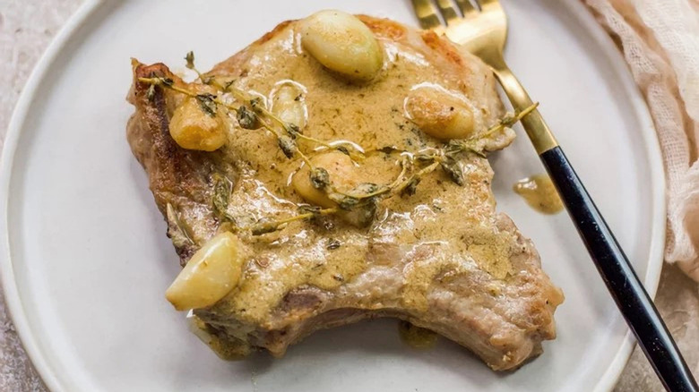 pork chop on plate with garlic and gravy