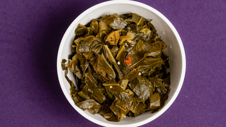 Collard greens in a white bowl on a purple background