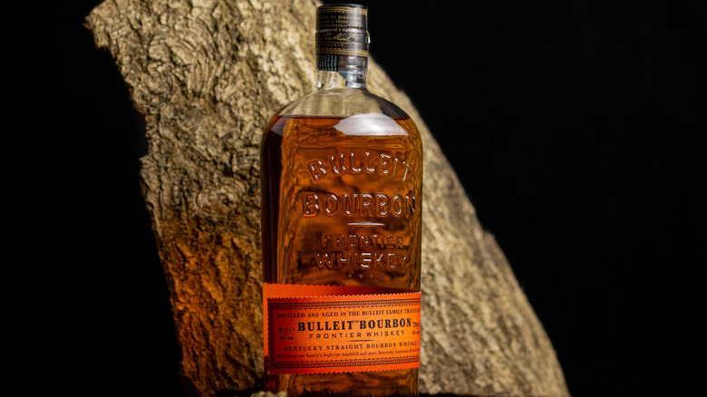 Bulleit Bourbon bottle in front of wood on black background