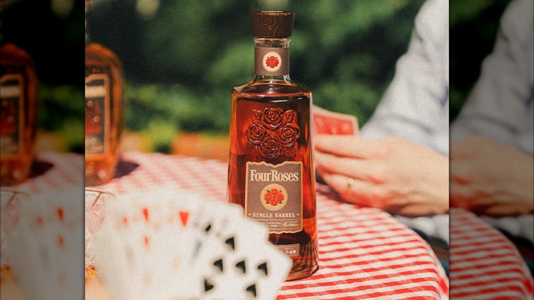Bottle of Four Roses Single Barrel on table with blurred people playing cards