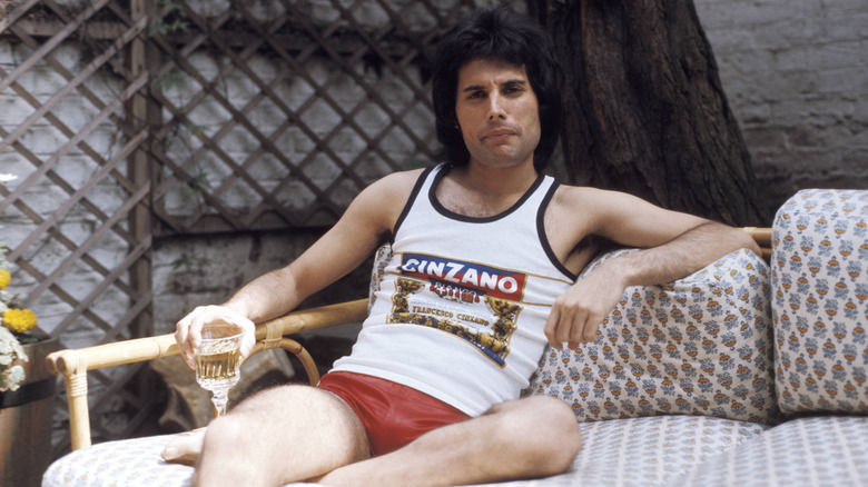 Freddie Mercury sitting on a sofa outdoors, holding a wine glass