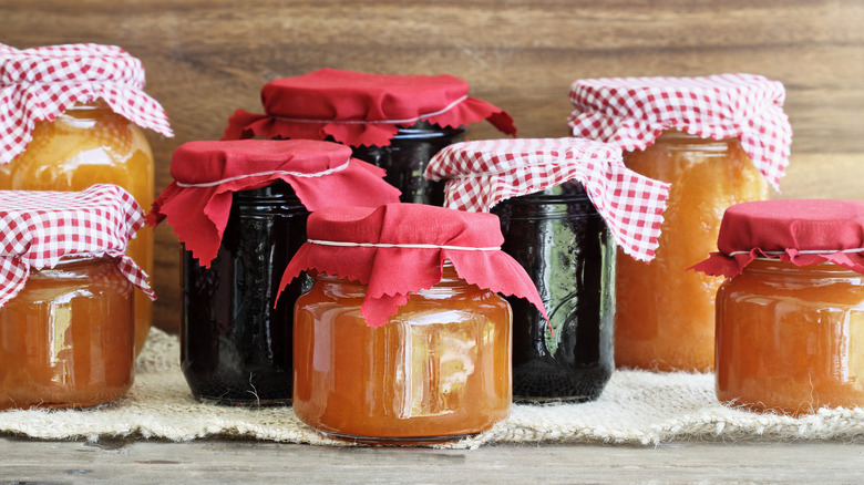 Jars of homemade jams and preserves, decorated with gingham and red cloths