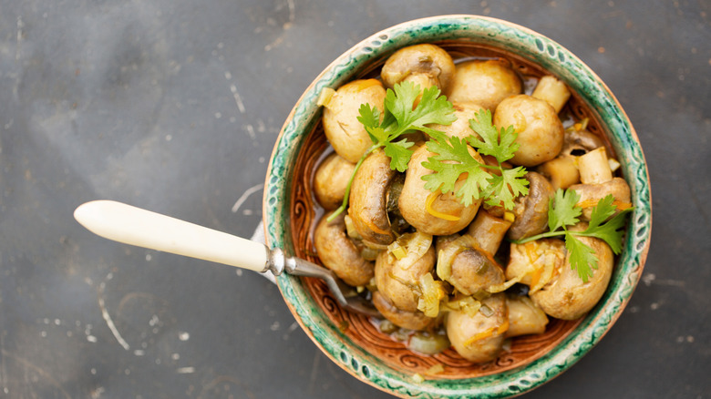 marinated whole mushrooms in a bowl with a spoon