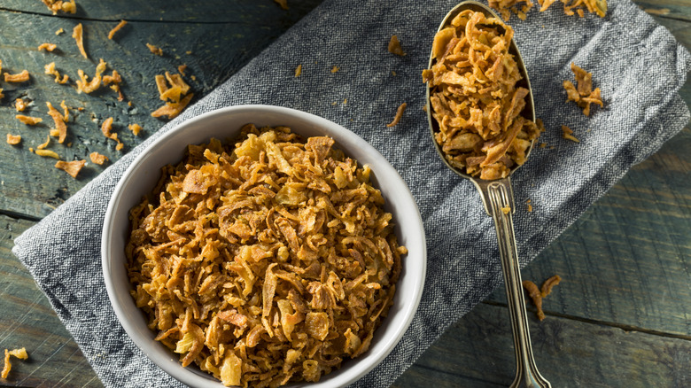 A bowl and spoon full of fried onion garnish