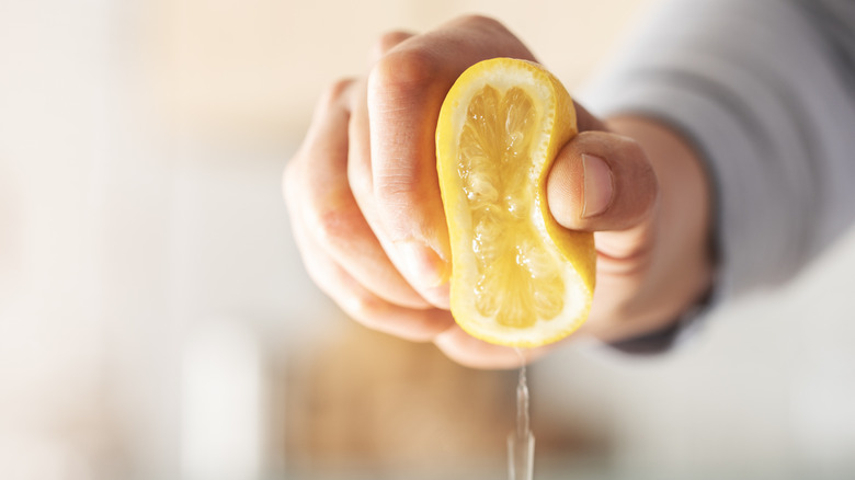 A hand squeezing half a lemon